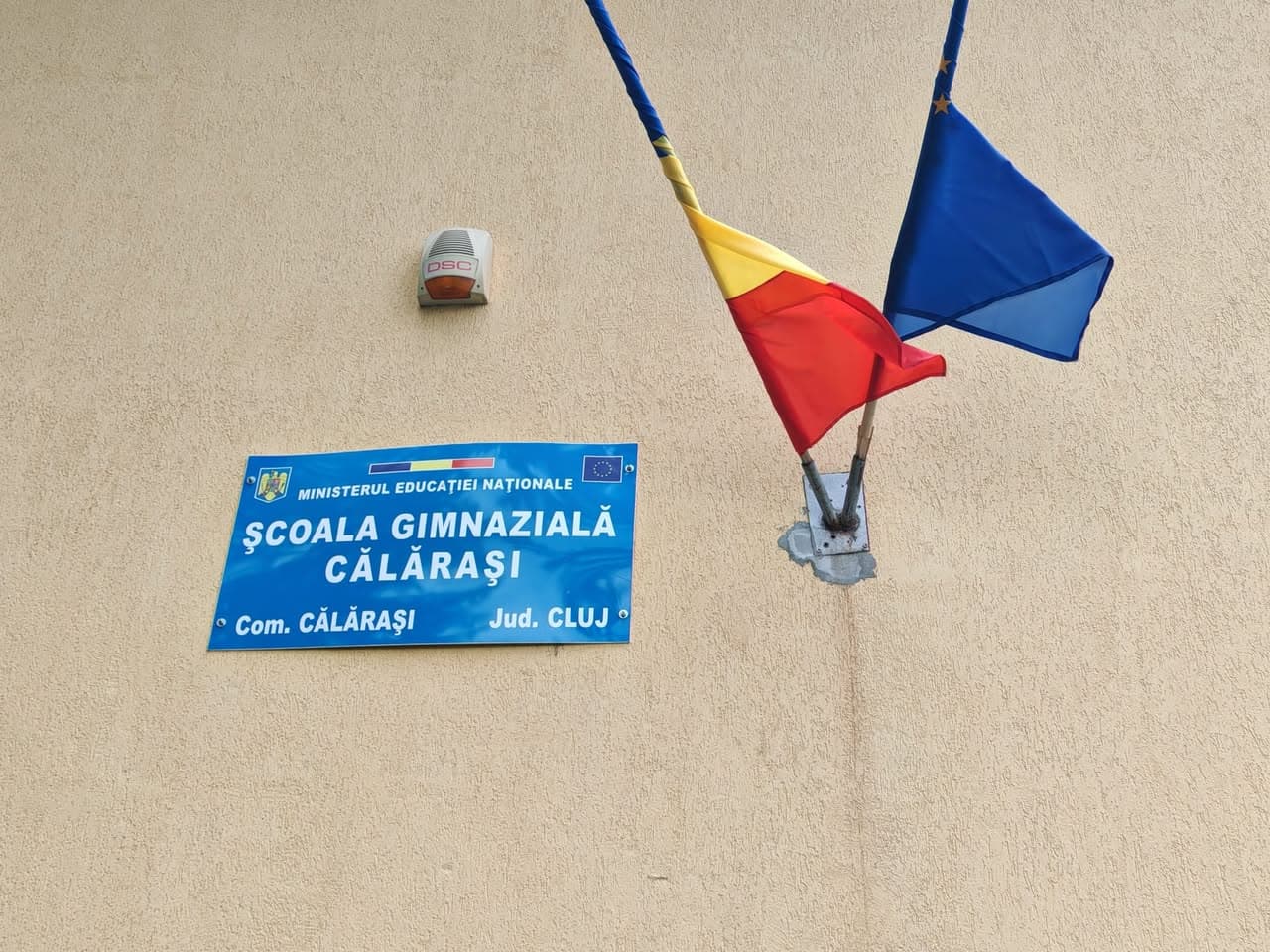 Fațada Școlii Gimnaziale Călărași, județul Cluj, cu drapelele României și Uniunii Europene