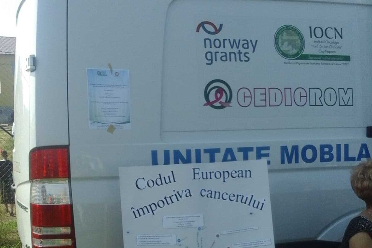 Unitatea mobilă de screening a Institutului Oncologic „Prof. Dr. Ion Chiricuță” Cluj-Napoca, cu afișul „Codul European împotriva cancerului” rezemat de bara din spate