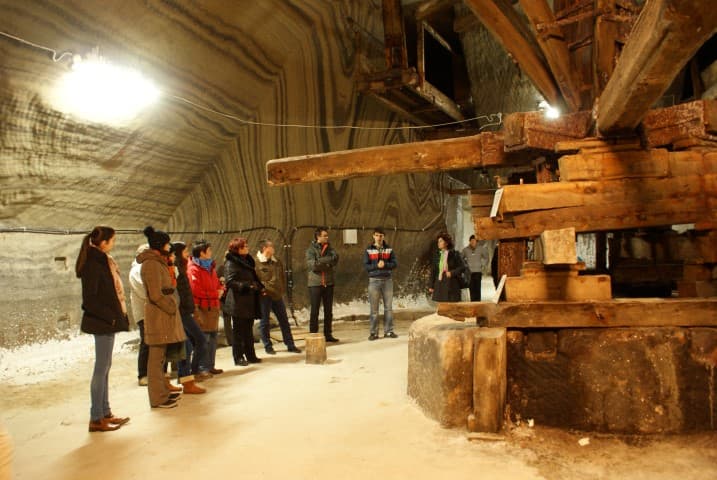 Grup de tineri din programul de schimb, în vizită în subteranul Salinei Turda, în fața utilajului de lemn din camera Rudolf